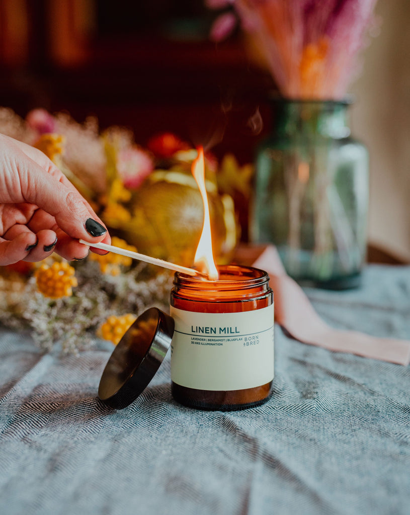 linen mill candle on table with flowers being lit